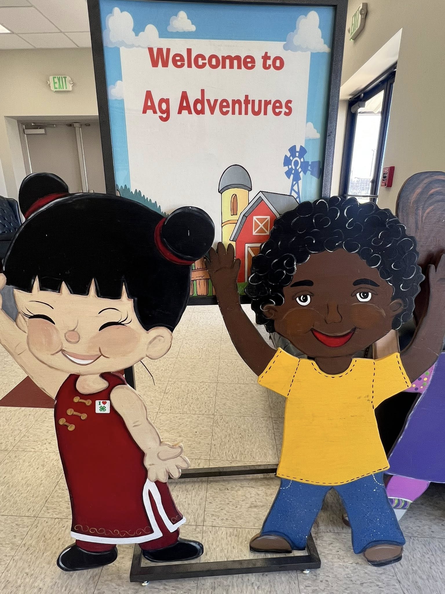 A sign that says Welcome to Ag Adventures and cartoon figures of a girl and a boy.